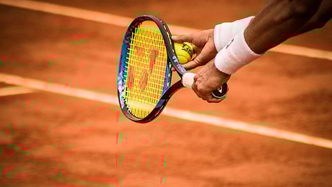 Close-up of a tennis player preparing to serve on a clay court