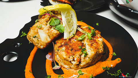 Fresh crab cakes topped with lemon and herbs on roasted pepper sauce
