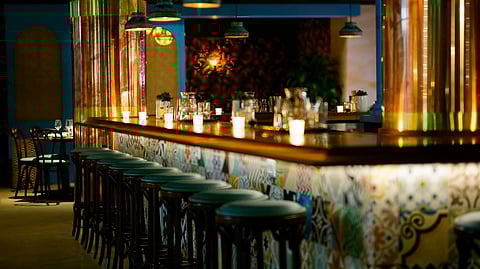 Candlelit bar at La Cañita with colorful tilework and wood stools.