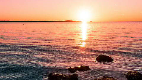 Sunset over the Adriatic Sea with soft pink and orange light reflecting on the water