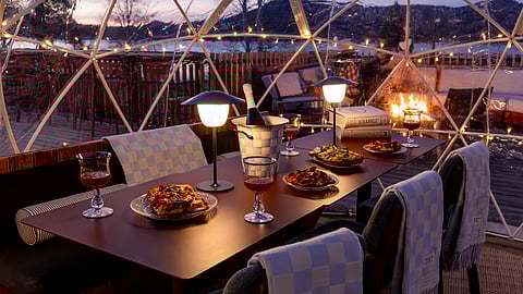 Dinner setup inside a glowing lakeside igloo at sunset