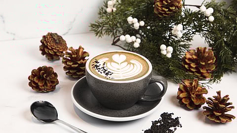 Black sesame latte with latte art styled with pinecones and holiday greenery