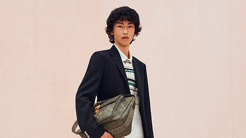 Model wearing a blazer, striped polo, plaid shorts, and Louis Vuitton crossbody bag