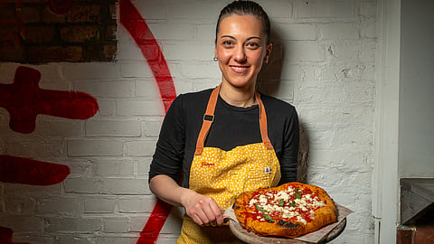Chef Giorgia Caporuscio holding a fried pizza inside Don Antonio restaurant