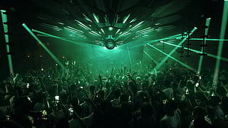 A packed crowd dancing beneath green lights inside Pacha Ibiza nightclub