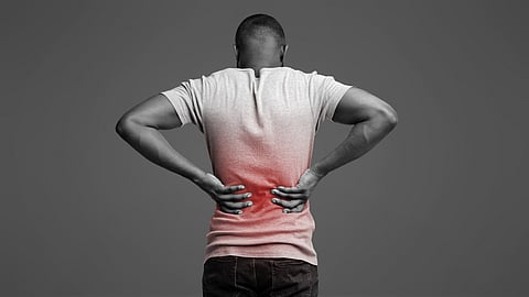 Man holding lower back with visible pain, illustrating chronic back pain and spinal discomfort