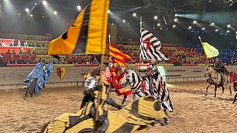 Knights on horseback wave banners during the opening procession at Medieval Times dinner theater