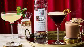 Ketel One Vodka with three Sundance cocktails on a marble bar against red curtains