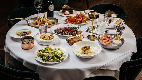 Table filled with steaks, seafood, sides, and desserts at Daniel’s Miami