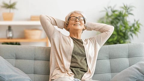 Older woman relaxing comfortably on a sofa in a bright, modern living space