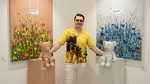 Artist Pieri posing between two mixed-media artworks with bear sculptures at LA Art Show 2026