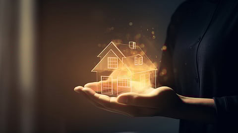 Glowing house outline hovering above open hands, symbolizing real estate investment
