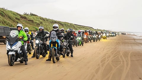 Motorcyclists ride along a sandy beach in Japan during the Sunrise–Sunset Touring Rally