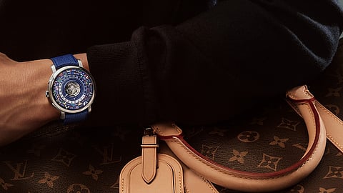 Escale Worldtime on wrist beside Louis Vuitton Monogram luggage