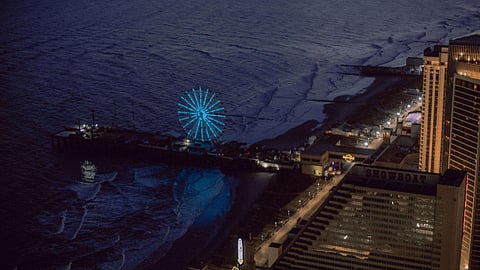 Aerial night view of Atlantic City boardwalk, ocean waves, and luxury hotels in New Jersey