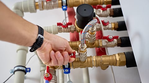 Close up of a hand adjusting a valve on a residential plumbing manifold system