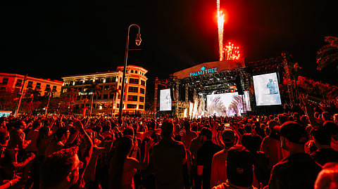 Fireworks burst above the Palm Tree stage as a packed crowd cheers at the waterfront festival
