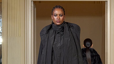 Model in layered black coat and fluid tailoring on Milan runway at Palazzo Bovara