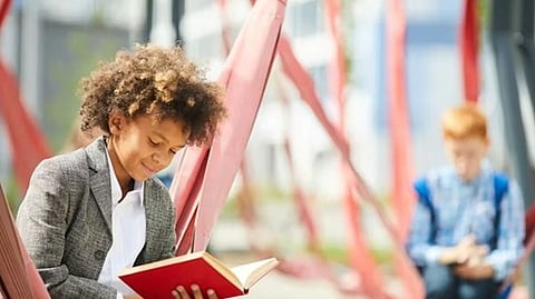 Student reading a book in an outdoor learning environment