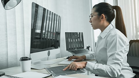 Engineer analyzing code on dual screens in a modern office setting