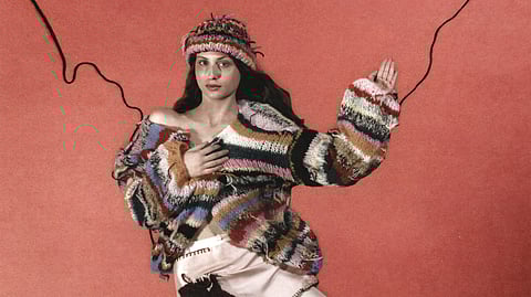 Model styled in striped handmade knit sweater, matching beanie, and pale skirt