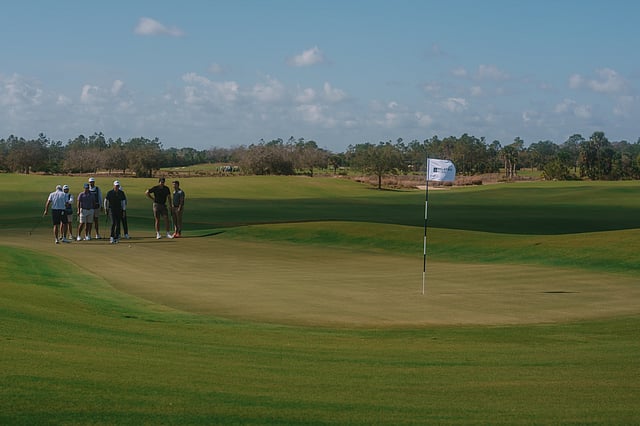 Players gather on the green during the Point72 and Related Ross Pro-Am in Palm Beach County