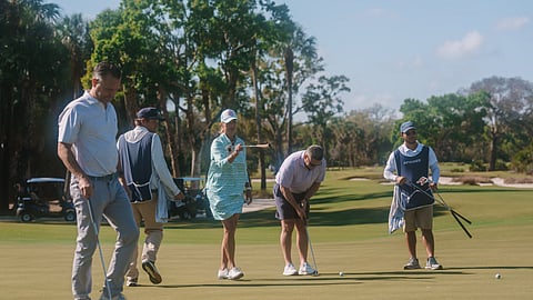 Participants line up putts on the green at Apogee Golf Club in Palm Beach County