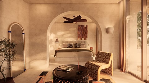 Standard guest room with arched alcove bed, woven chair, and warm natural light