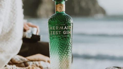 Bottle of Mermaid Zest Gin on coastal rocks 