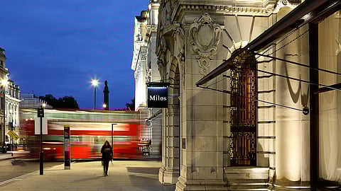 estiatorio Milos Midtown exterior with illuminated facade and passing city bus