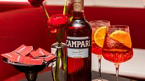 Campari bottle with spritz cocktails and orange garnish at aperitivo event