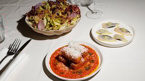 Crispy polenta with tomato sauce, citrus crudo, and butter lettuce salad on table
