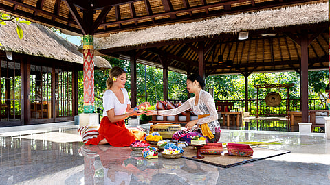 Guest and host create traditional flower offerings in open-air pavilion at HOSHINOYA Bali