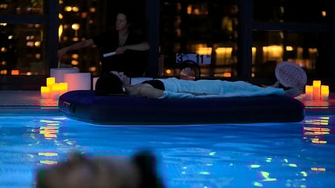 Guest floating in a pool during a candlelit sound bath session at a luxury spa