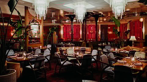 Elegant dining room with chandeliers, red walls, and candlelit tables in a supper club setting