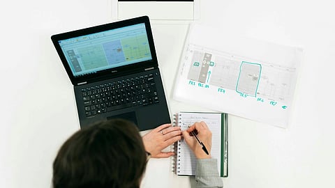 Overhead view of person using laptop and notebook with workflow diagrams for ERP planning
