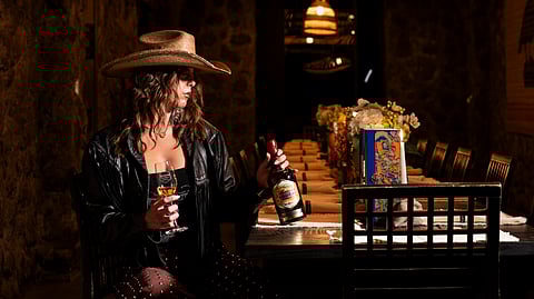Guest holds a tequila glass and bottle inside Tequila Town immersive installation in Miami