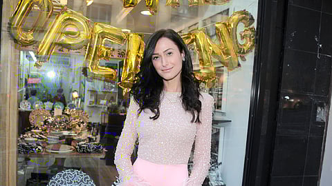 Elizabeth Sutton standing outside her atelier storefront with gold balloons