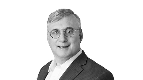 Peter Fields in a suit and glasses posing in a studio portrait against a light background