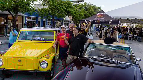 Guests gather beside vintage cars during Antique Row street festival