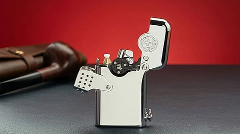 Open Swiss mechanical lighter beside a pipe on a tabletop