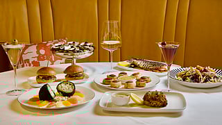 Assorted dishes including oysters, sliders, crab cake, salad, and cocktails