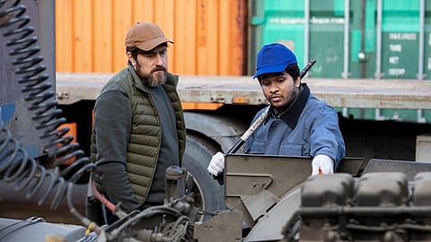 Workers inspect equipment at a job site while managing construction debris