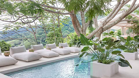 Lush poolside lounge with cushions overlooking tropical mountain landscape in Costa Rica