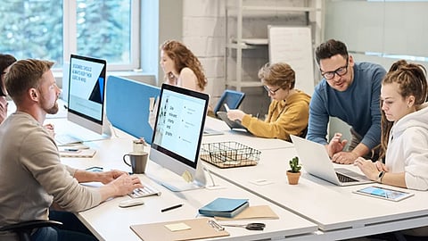Team collaborating in a modern office using computers to manage digital records and workflows