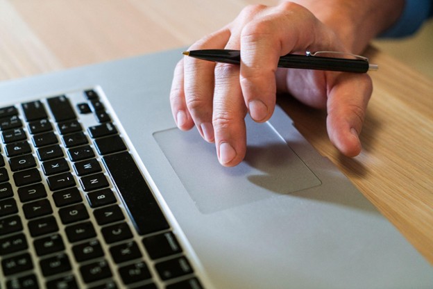 Person using laptop trackpad with pen, symbolizing digital resource management and automation