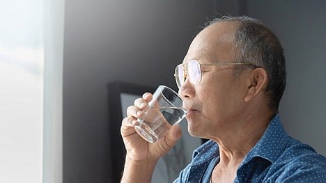 Man drinking water indoors representing hydration habits and health support for limited mobility