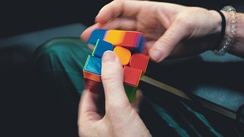 Hands twisting puzzle cube, symbolizing cognitive training and mental exercises