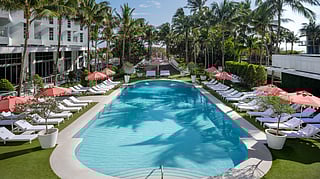 Resort pool lined with palm trees and loungers at Cadillac Hotel & Beach Club