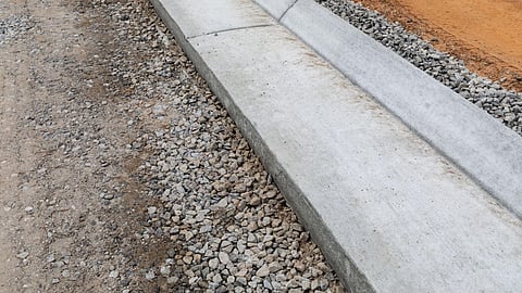 Concrete curb edging installed along gravel and dirt landscaping border